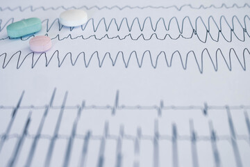 Cardiovascular disease concept. Selective focus. Colored pills on electrocardiograms with...