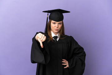 Young university graduate over isolated purple background showing thumb down with negative expression