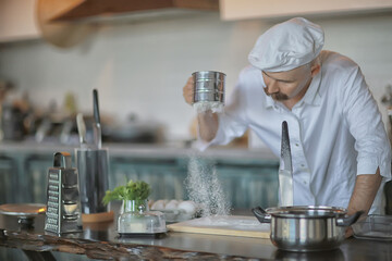 french chef in the kitchen preparing food, cooking, haute cuisine, man with mustache