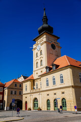 Fototapeta na wymiar Yellow classic town hall with clock tower at main Freedom square, renaissance and baroque historical buildings, blue sky, Medieval street, sunny day, Zatec, Bohemia, Czech Republic