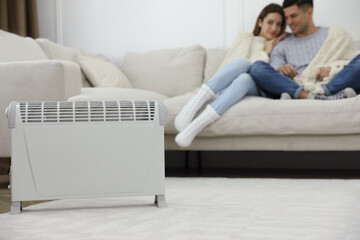 Electric heater and couple on sofa at home