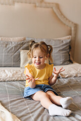 Fototapeta premium Portrait of little preschool girl fooling around on bed at home