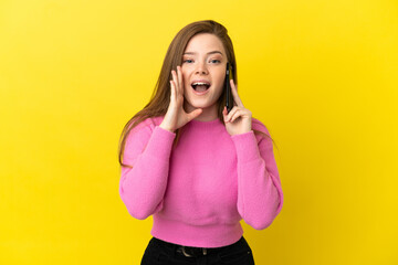 Teenager girl using mobile phone over isolated yellow background shouting with mouth wide open