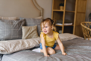 Portrait of little preschool girl fooling around on bed at home
