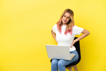 Naklejka premium Young woman sitting on a chair with laptop over isolated yellow background suffering from backache for having made an effort