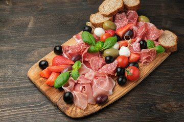Salami prosciutto parma ham serving with olives strawberries on wooden board