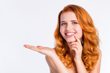 Photo portrait of pretty girl with curly red hair smiling keeping empty space on palm isolated on white color background