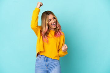 Young woman over isolated blue background celebrating a victory