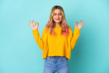 Young woman over isolated blue background in zen pose