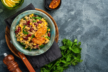 Mexican black bean corn quinoa salad with caramelized lemon in old vintage clay bowl on a dark gray concrete background. Traditional Mexican cuisine dish. Top view, mock up.