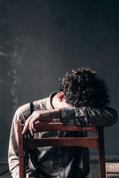 Alone boy in depression with cigarette in vintage a dark room.