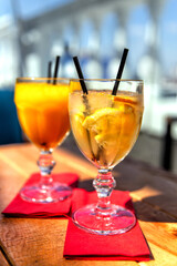 Two glass with lemonade or mojito cocktail with lemon, cold refreshing drink or beverage with ice on blur background