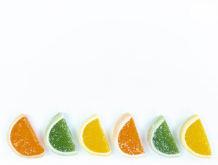 Fototapeta na wymiar Multicolored marmalade citrus slices in sugar on white background with copy space.