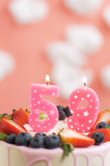 Birthday cake number 59. Beautiful pink candle in cake on pink background with white clouds. Close-up and vertical view