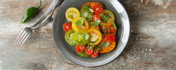 plate with tomato and basil salad on wooden table