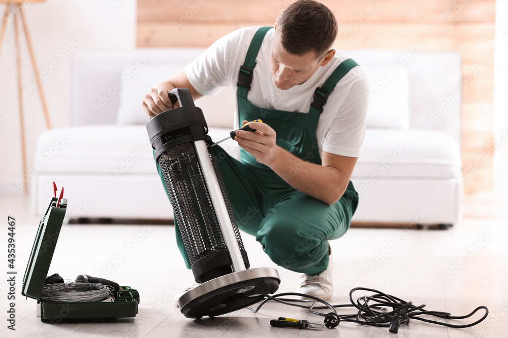 Canvas Prints Professional technician repairing electric patio heater with screwdriver indoors