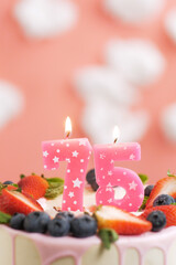 Birthday cake number 75. Beautiful pink candle in cake on pink background with white clouds. Close-up and vertical view