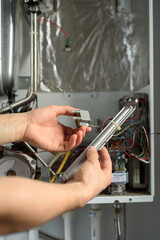 A man checks a gas boiler for home heating. Maintenance and repair of gas heating