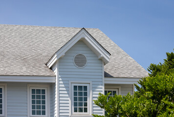 Roof shingles with garret house on top of the house among a lot of trees. dark asphalt tiles on the...