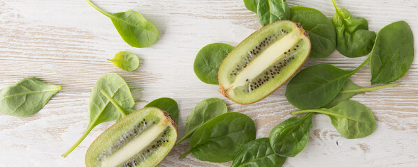baby spinach and kiwi halves on a light wooden table
