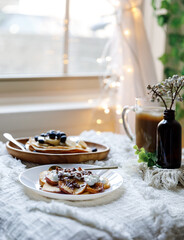 Pancakes with peaches, blueberries and banana in a cozy setting 