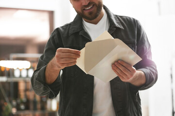 Man holding envelope with greeting card indoors, closeup © New Africa