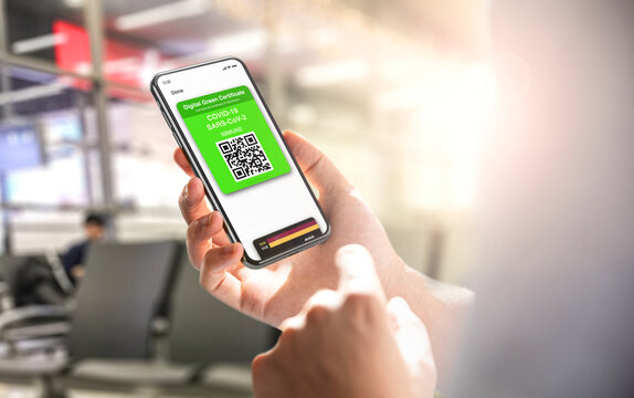 Digital green card certificate with covid-19 immune on smartphone screen. Blurred airport interior in background