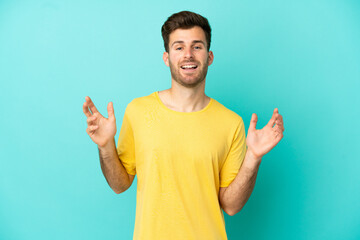 Fototapeta premium Young caucasian handsome man isolated on blue background smiling a lot