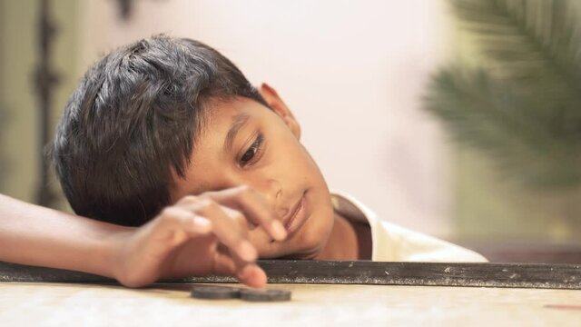 Lazy kid playing carrom by sleeping on board - concept of boredom , brain development and childhood lifestyle