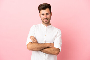 Young caucasian handsome man isolated on pink background keeping the arms crossed in frontal position