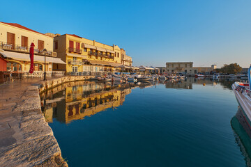 Fototapeta na wymiar the quay of the historic harbour of Rethymno in the morning sun, boats in the port and still closed restaurants