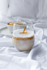 Dalgona coffee with apple oatmeal breakfast on white cozy bed