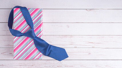 Happy Father's Day with a blue tie and a gift box on wooden background with space for text. Top view. Flat lay