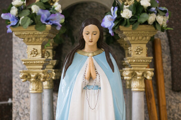 Mother Mary pray. Blessed virgin statue. Rosary in hands.