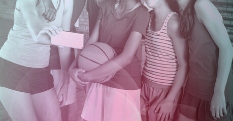 Composition of girl taking photo with smartphone of team of school basketball players