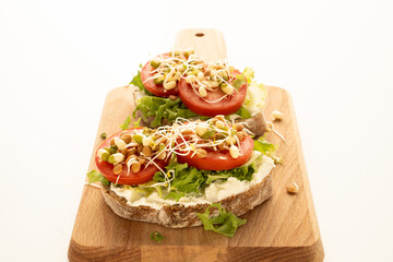 Sandwiches with cream cheese, tomatoes and bean sprouts on the wooden board