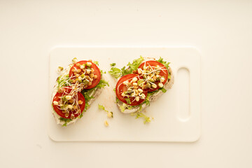 Sandwiches with cream cheese, tomatoes and bean sprouts on the white board. Top view. 
