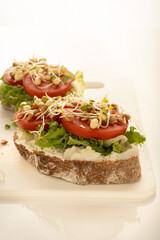 Sandwiches with cream cheese, tomatoes and bean sprouts on the white board