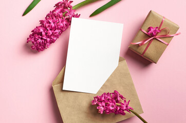 Greeting or invitation card mockup with envelope, gift box and fresh hyacinth flowers on pink