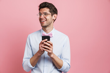 Young white man wearing bow tie smiling and using cellphone