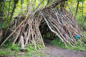 Aus Ästen und Holz errichtete Schutz- und Spielhütten stehen in einem grünen Waldgebiet. Das...