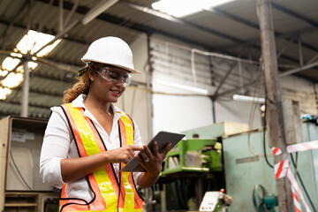 Factory woman worker at work in the industry factory, work with digital tablet with happy and smile. Female worker maintaining machine in the industrial plant
