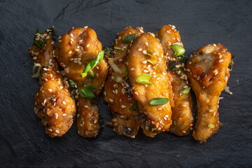 fried teriyaki chicken wingson a dark slate, stone or concrete background