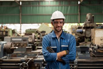 Portrait of male factory worker working and standing in front of manufacturing machinery in the...