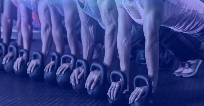 Composition of mid section of fit people doing press ups on kettlebells in gym with purple tint