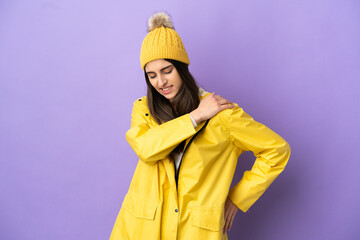 Young caucasian woman wearing a rainproof coat isolated on purple background suffering from pain in shoulder for having made an effort