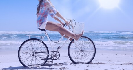 Fototapeta premium Composition of woman riding bike on beach with copy space