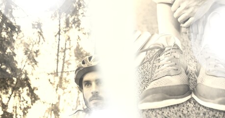 Composition of male cyclist in helmet with overexposure and person putting on shoes on in sepia tone