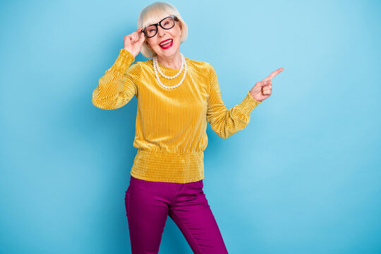 Photo of funny short hairdo aged lady point empty space wear blouse eyewear isolated on blue color background