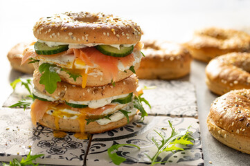 Fresh healthy sandwiches with seeded bagel, mayo, salmon, egg, cucumber and rocket